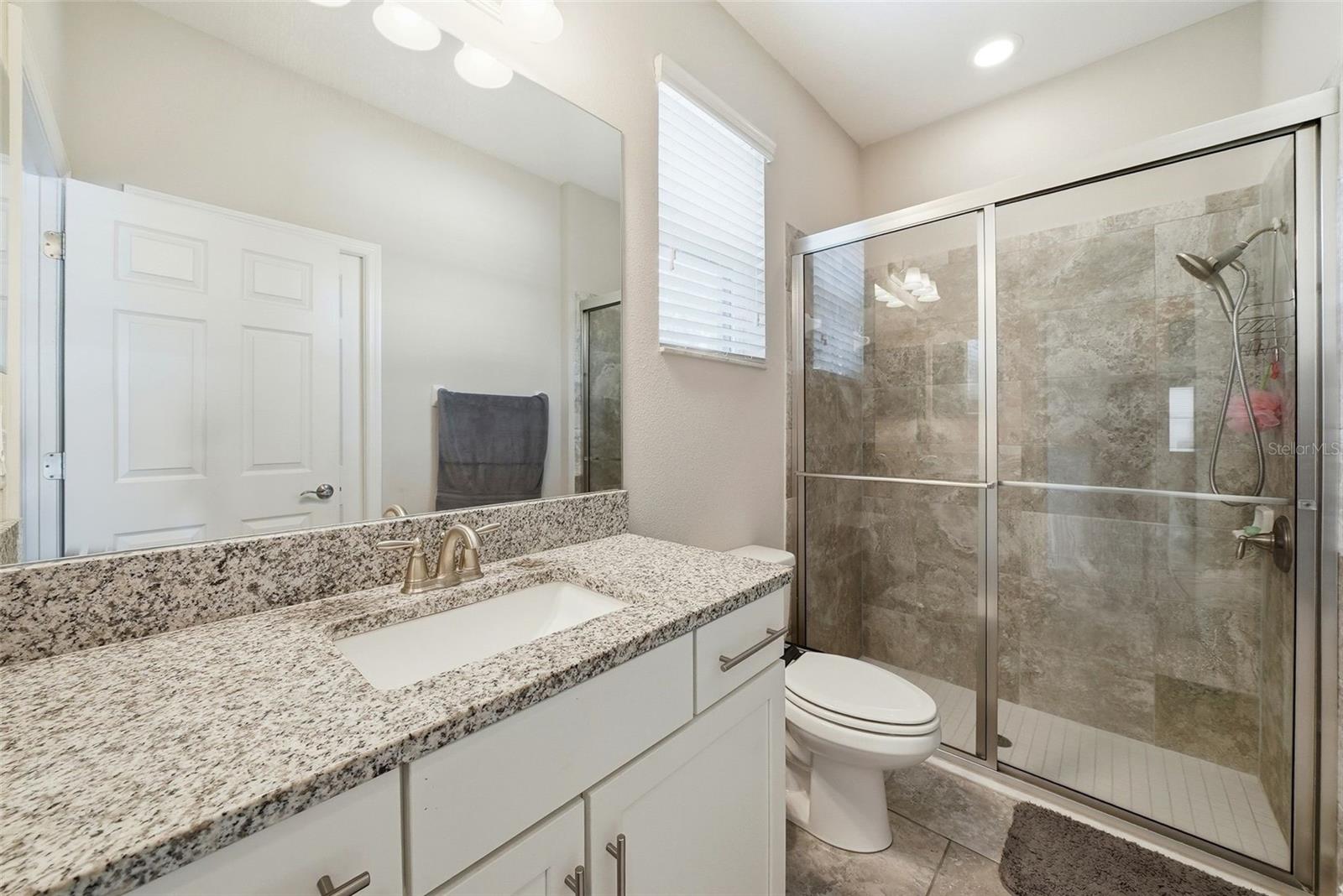 The main level bathroom is thoughtfully designed with convenient access to both the pool area and the main-level bedroom, making it ideal for guests and everyday use. Its layout provides seamless indoor to outdoor flow while also perfectly serving as a private bath option for the main-level bedroom.