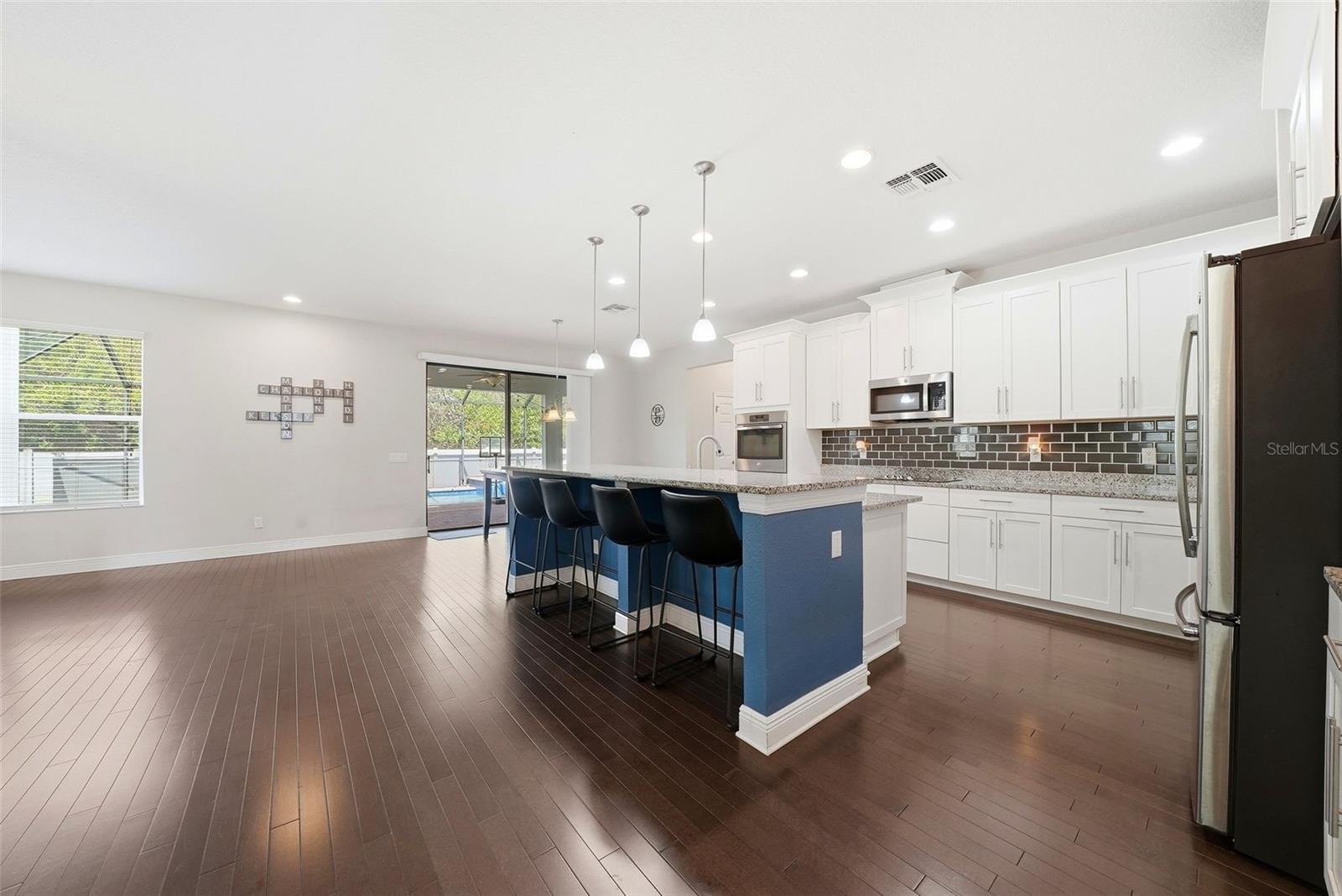 The kitchen is beautifully appointed with granite countertops, double ovens, and stainless steel appliances, all centered around an oversized island perfect for gathering and entertaining. A spacious pantry and abundant cabinetry provide exceptional storage, combining style and functionality in a truly impressive space.