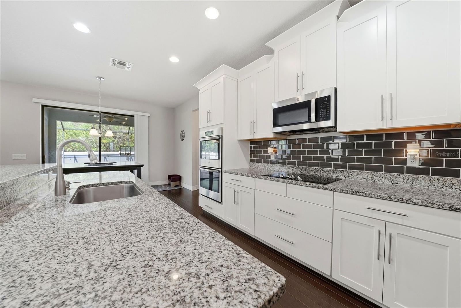 The kitchen is beautifully appointed with granite countertops, double ovens, and stainless steel appliances, all centered around an oversized island perfect for gathering and entertaining. A spacious pantry and abundant cabinetry provide exceptional storage, combining style and functionality in a truly impressive space.