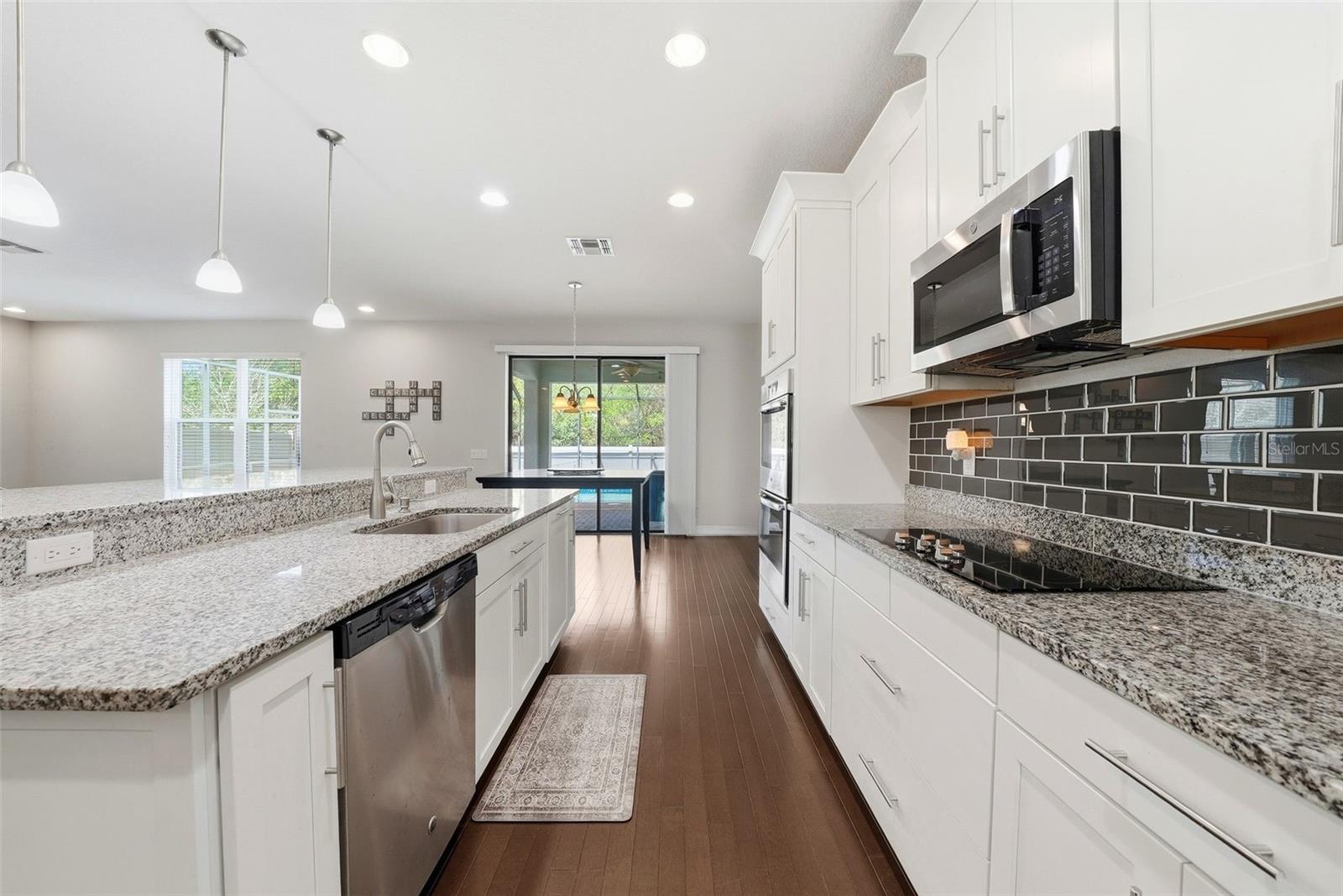 The kitchen is beautifully appointed with granite countertops, double ovens, and stainless steel appliances, all centered around an oversized island perfect for gathering and entertaining. A spacious pantry and abundant cabinetry provide exceptional storage, combining style and functionality in a truly impressive space.