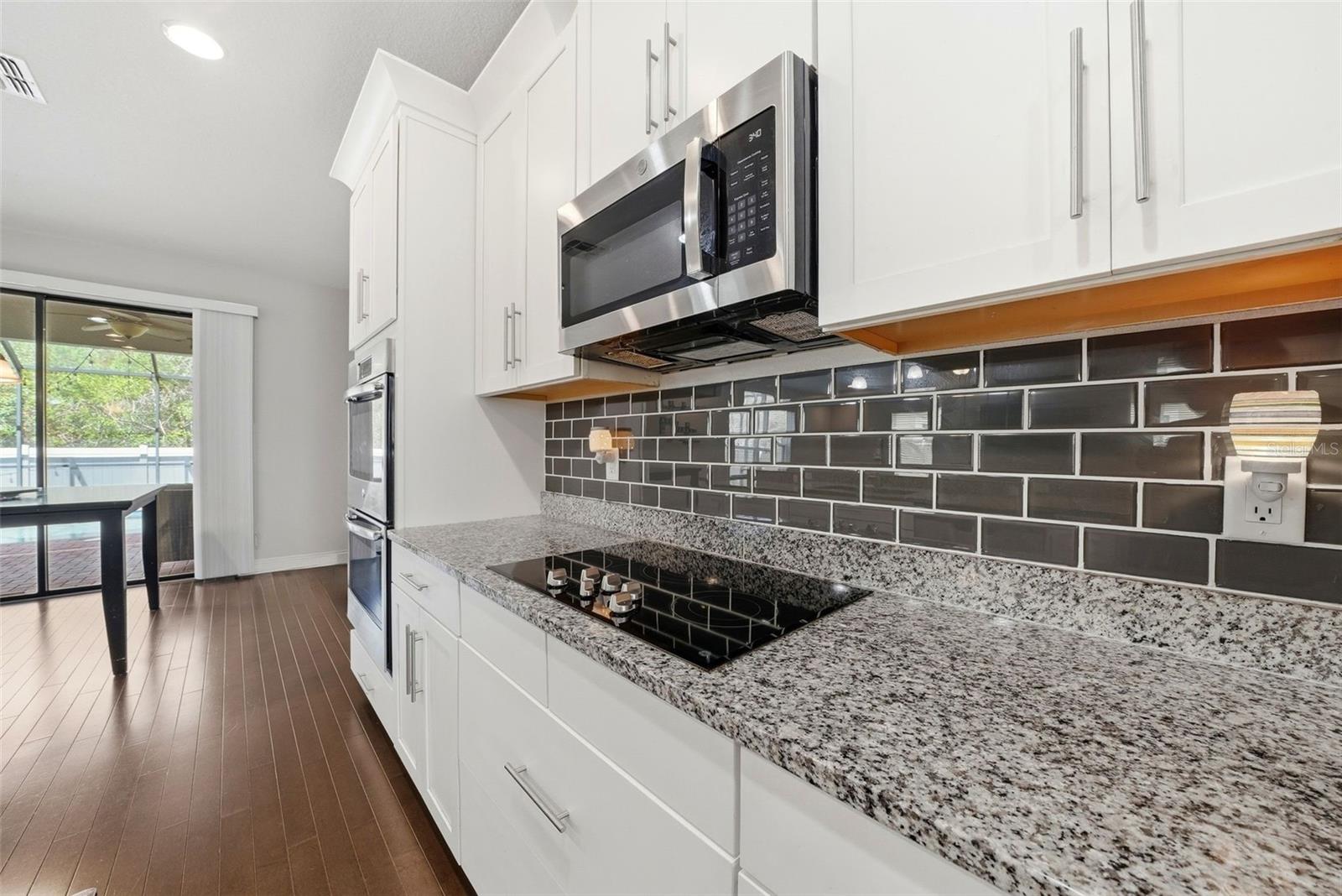 The kitchen is beautifully appointed with granite countertops, double ovens, and stainless steel appliances, all centered around an oversized island perfect for gathering and entertaining. A spacious pantry and abundant cabinetry provide exceptional storage, combining style and functionality in a truly impressive space.