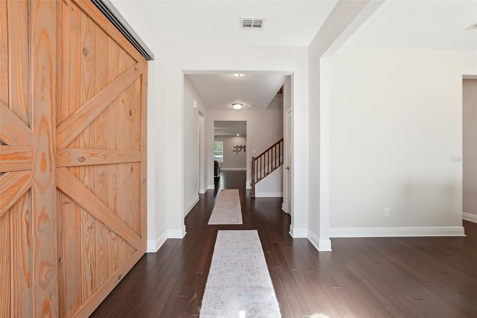 A private office tucked behind stylish barn doors offers both function and character, while the formal dining room to the right of the entry creates an elegant and welcoming space for entertaining.
