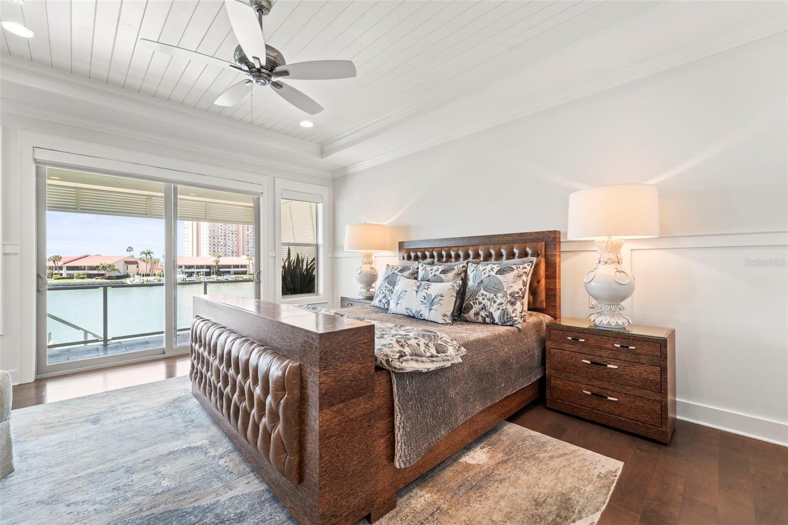 The primary suite features west-facing sliding glass doors and screen that open to the covered lanai and capture breathtaking sunset views. Complete with upgraded millwork, wainscoting, coffered ceilings & remote operated Hunter Douglas shades
