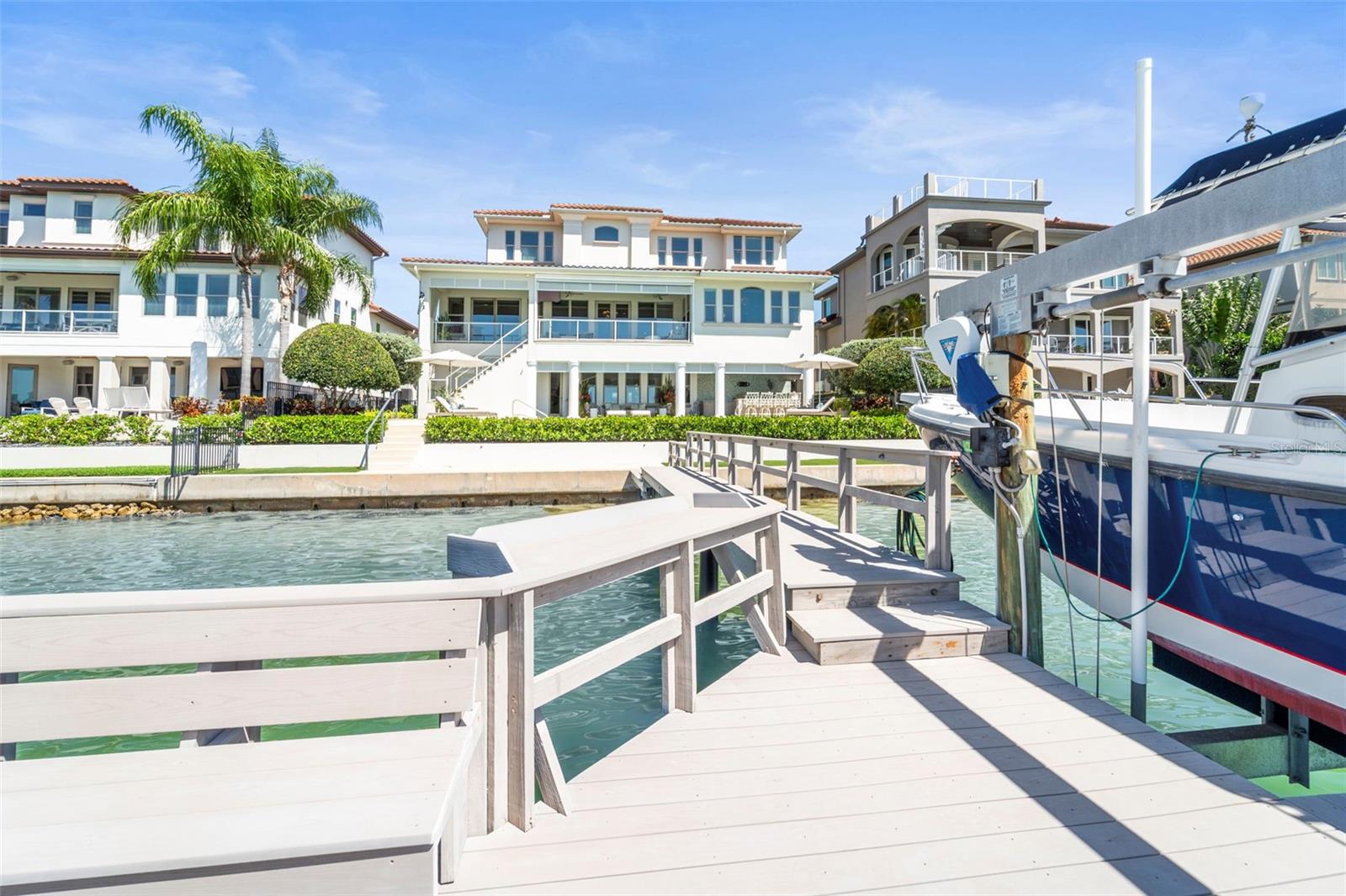 Rear exterior of the waterfront home featuring the poo/spa, covered lanais with outdoor kitchen and private dock