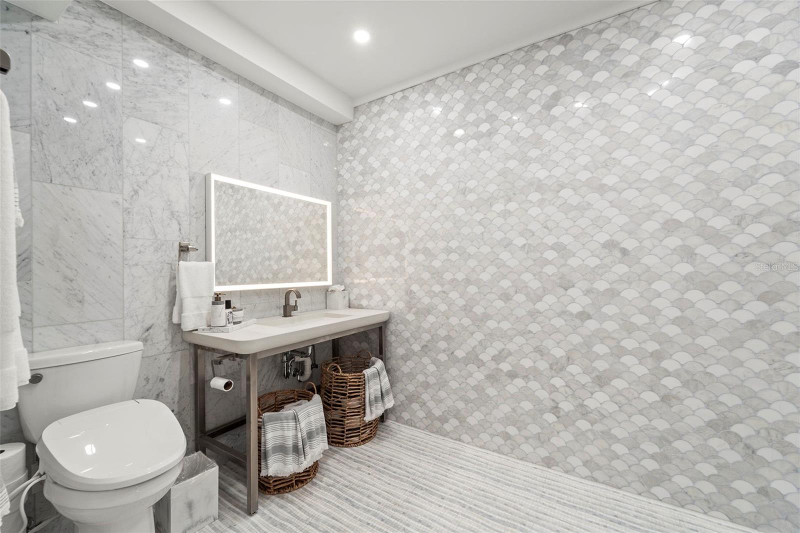 Garage-level bathroom featuring handmade Italian marble tile, bide, and dual shower heads.