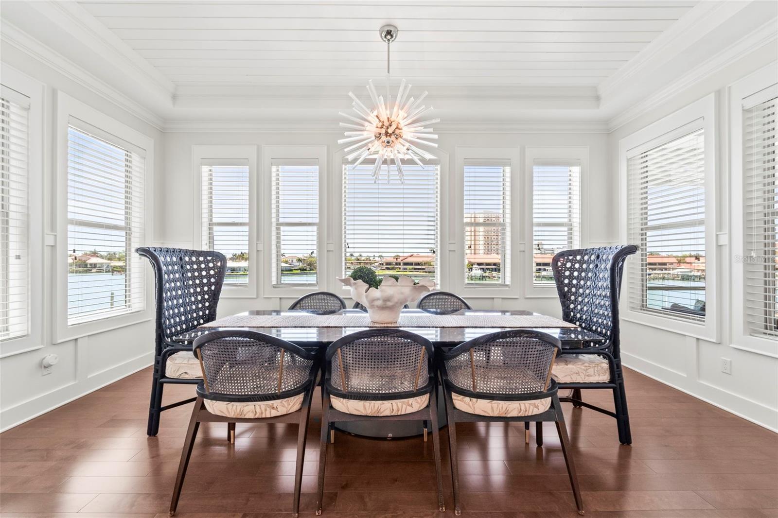 Formal dining room surrounded by large windows with beautiful water views, gorgeous lighting and custom blinds