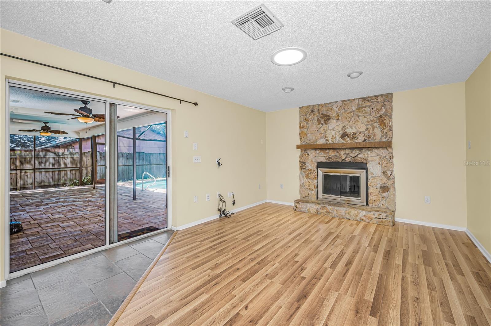 Family room with wood burning fireplace opens to pool