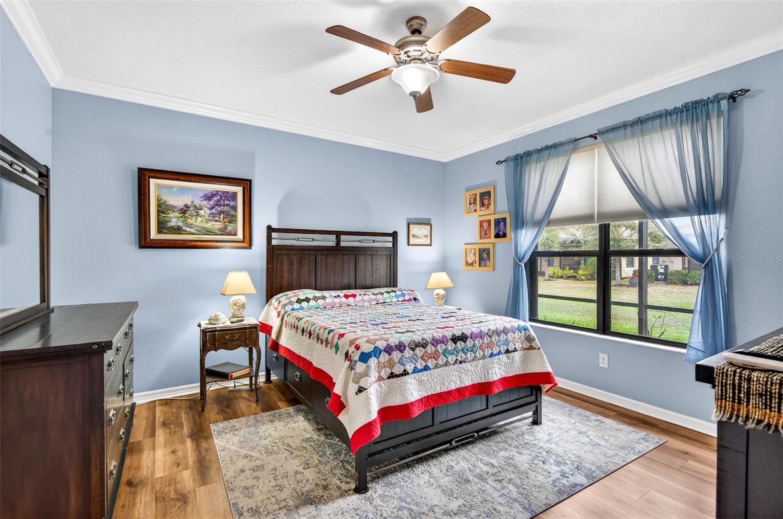 Primary bedroom with large window that brings in the natural light. Ceiling fan and crown molding. Luxury vinyl plank flooring.