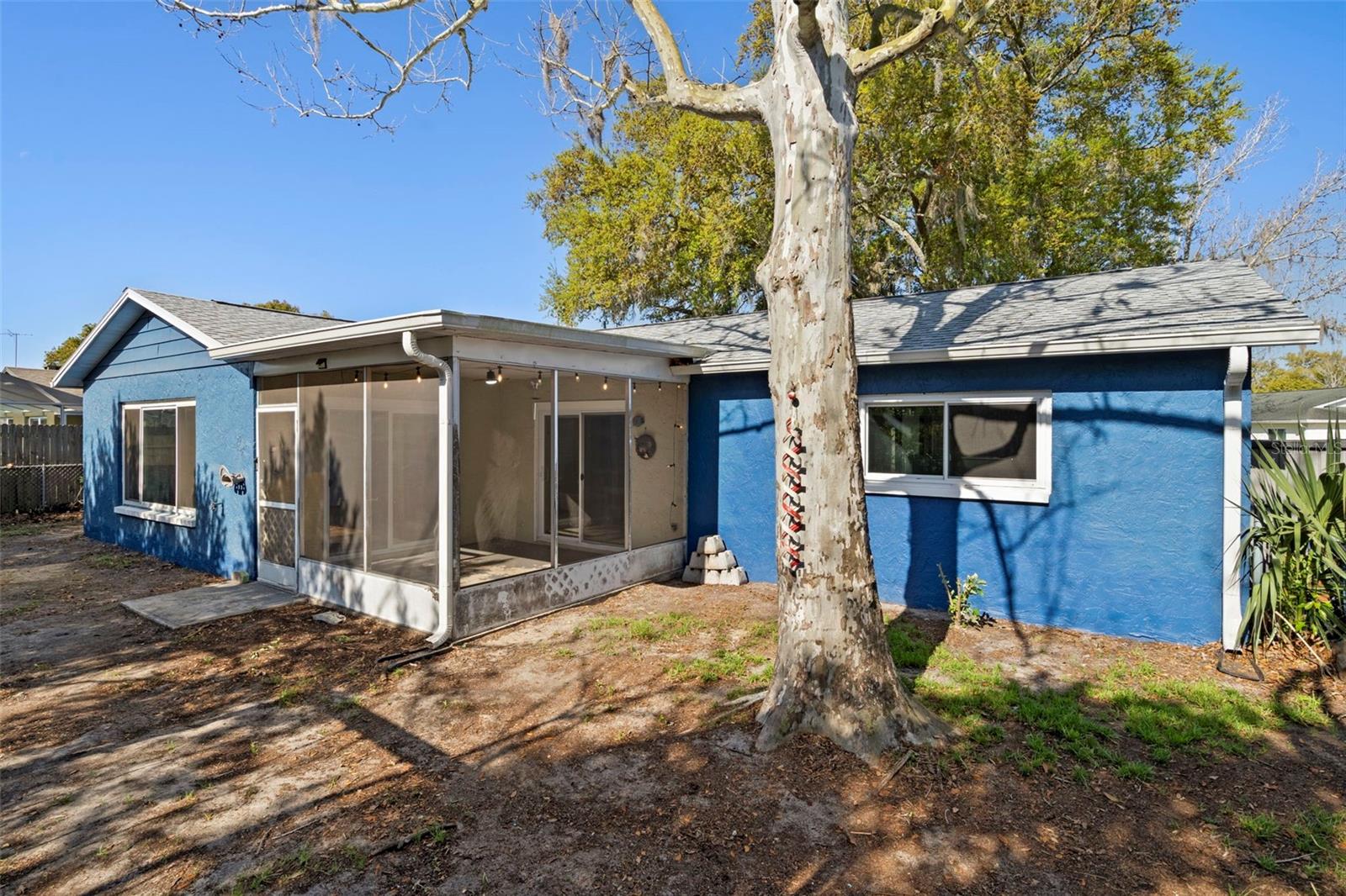 back of home with screened lanai and fenced backyard