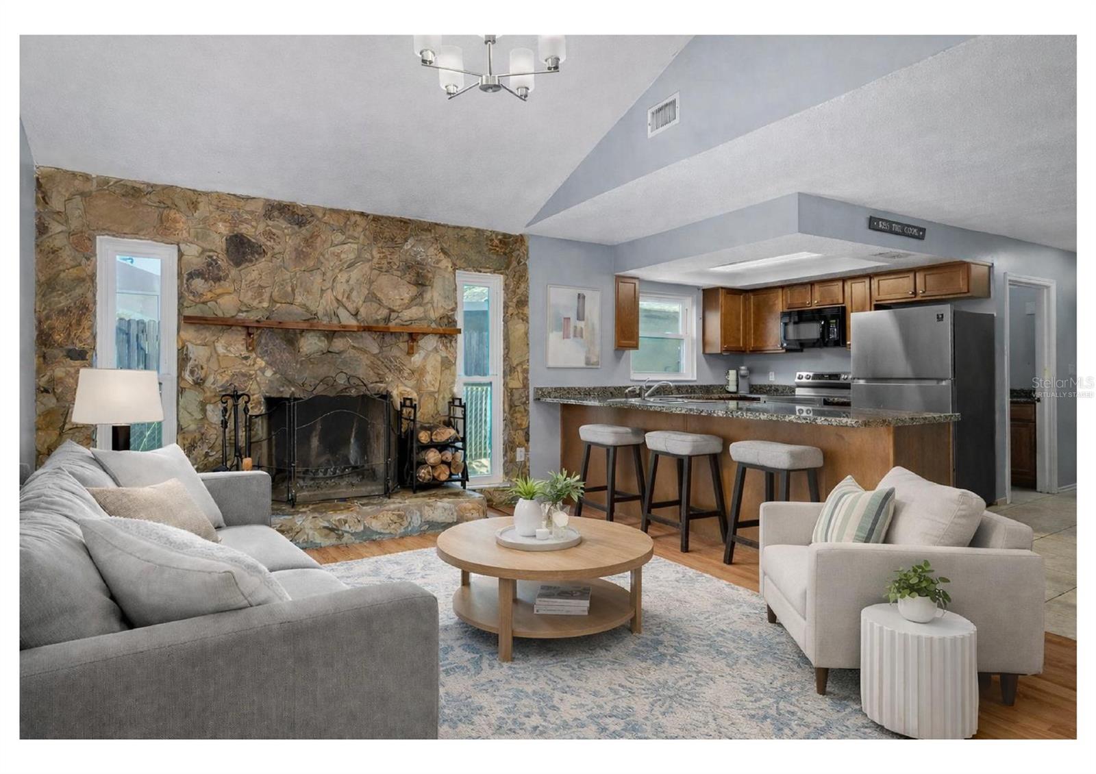 Family room with vaulted ceiling and wood-burning stone fireplace. Furniture shown is virtually staged