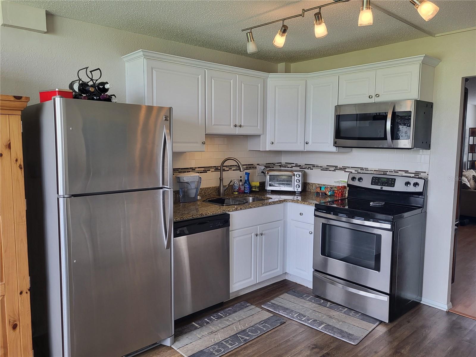 Kitchen with granite and stainless appliances. Refrigerator, dishwasher, microwave, and range.