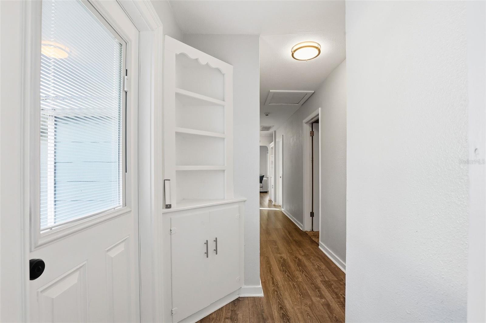 hallway with door to backyard and built in closet/bookshelves
