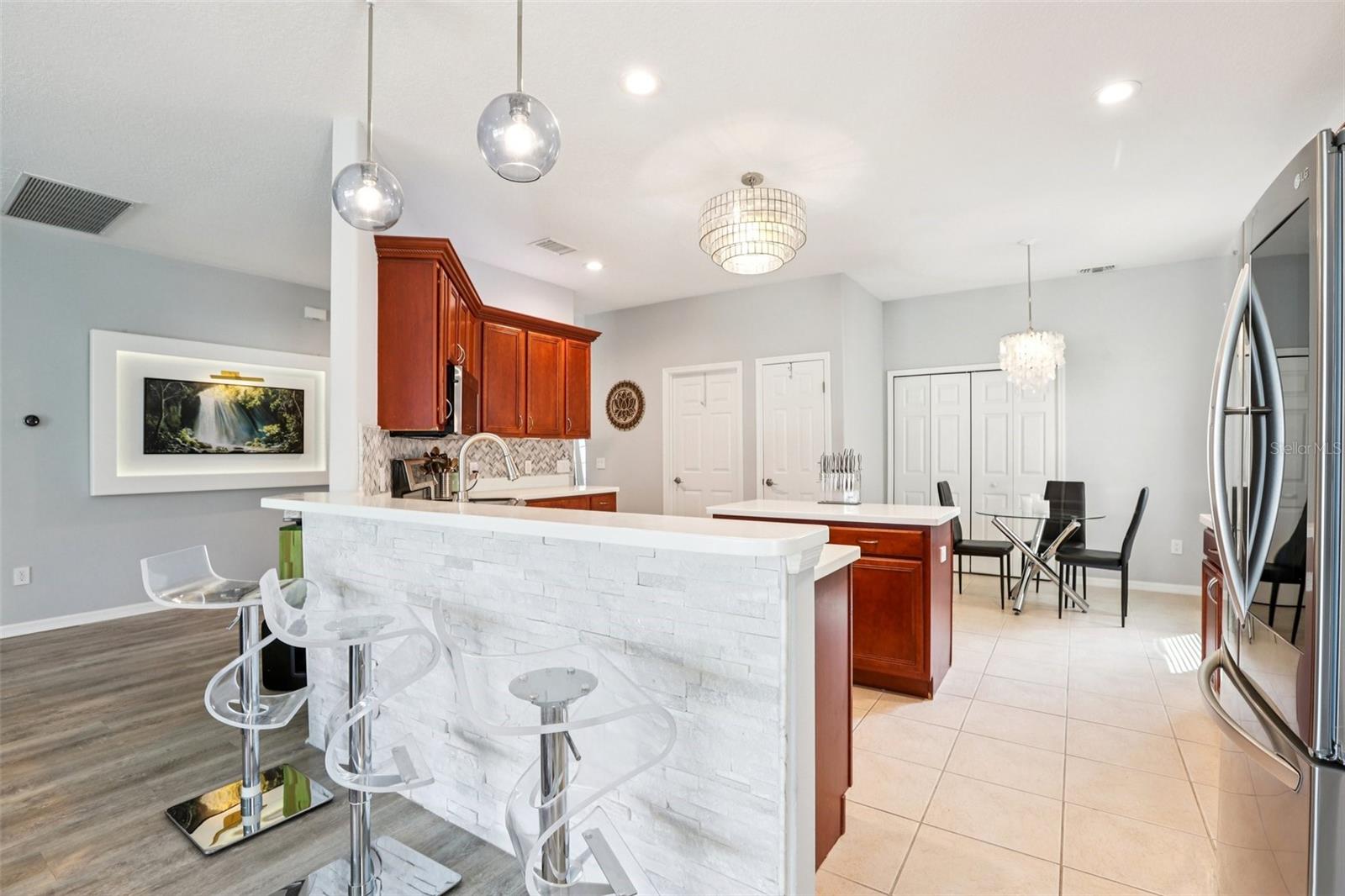 Kitchen with tear-drop lights open to Family Room