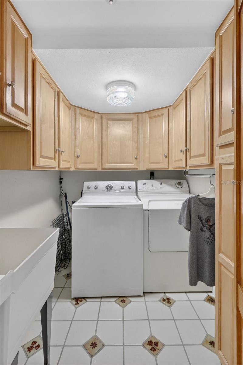 Laundry room with built in cabinets for extra storage, along with a utility sink, inside the home