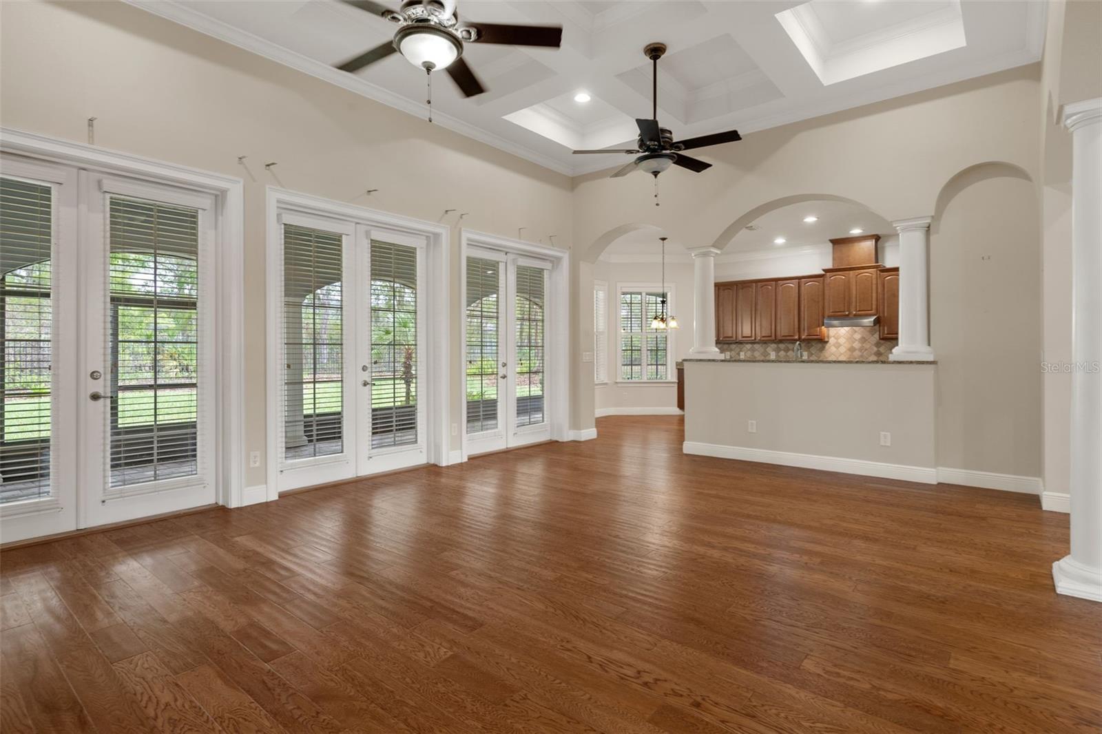 Living Room with Hardwood Floors and Triple French Doors to Covered Lanai