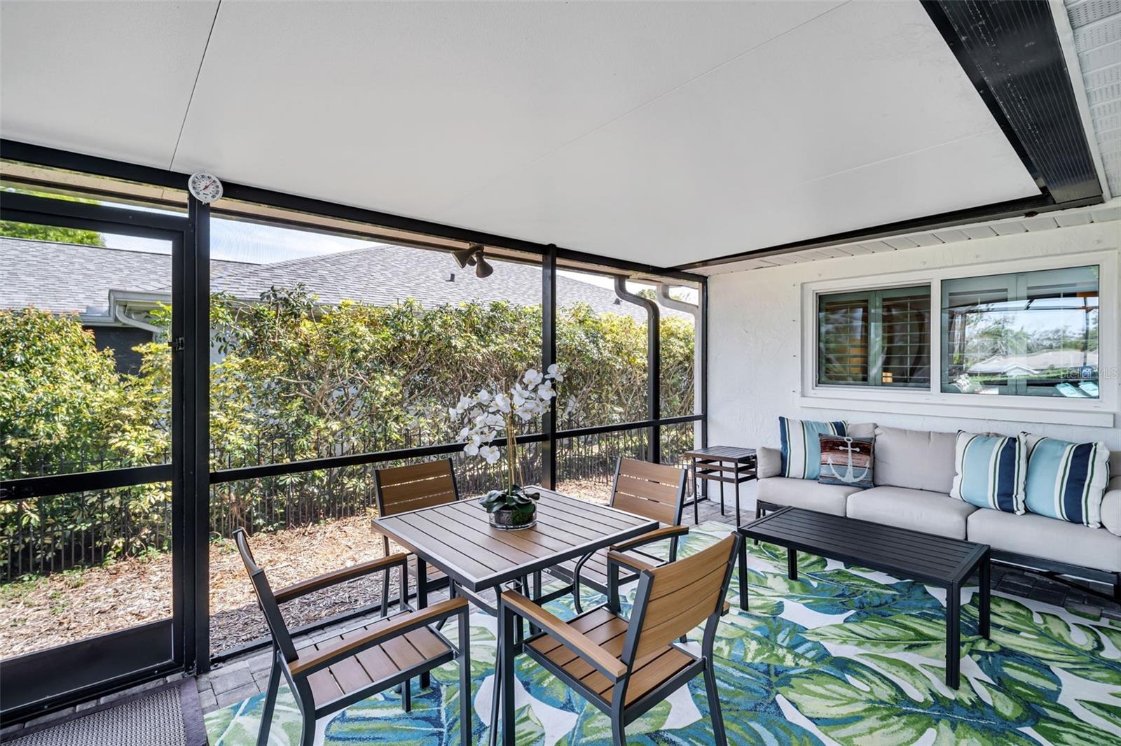 Covered pool patio on side of house that leads to a fenced area outside the screen for pets~