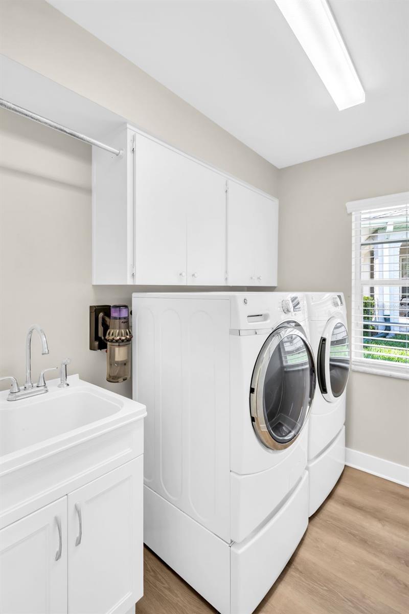 Large indoor laundry with newer washer/dryer, convenient utility sink, and additional cabinetry for storage~