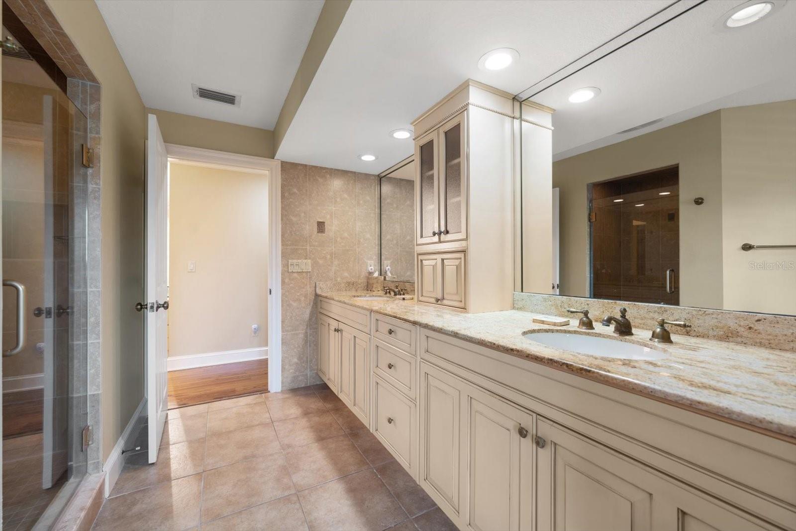 Spacious primary bathroom area has dual vanity areas with tower storage.