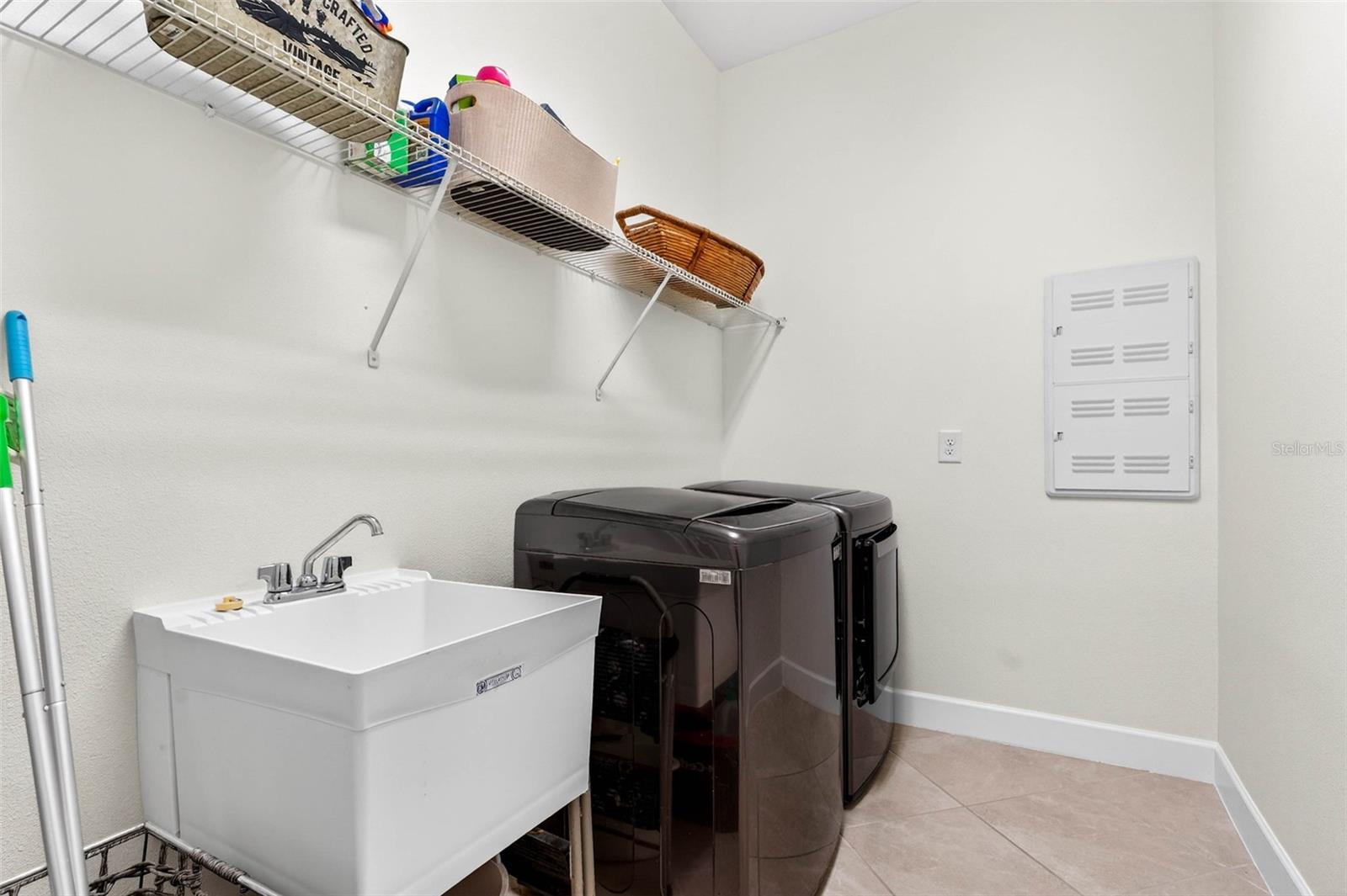 Laundry room has overhead shelving and sink basin for easy wash.