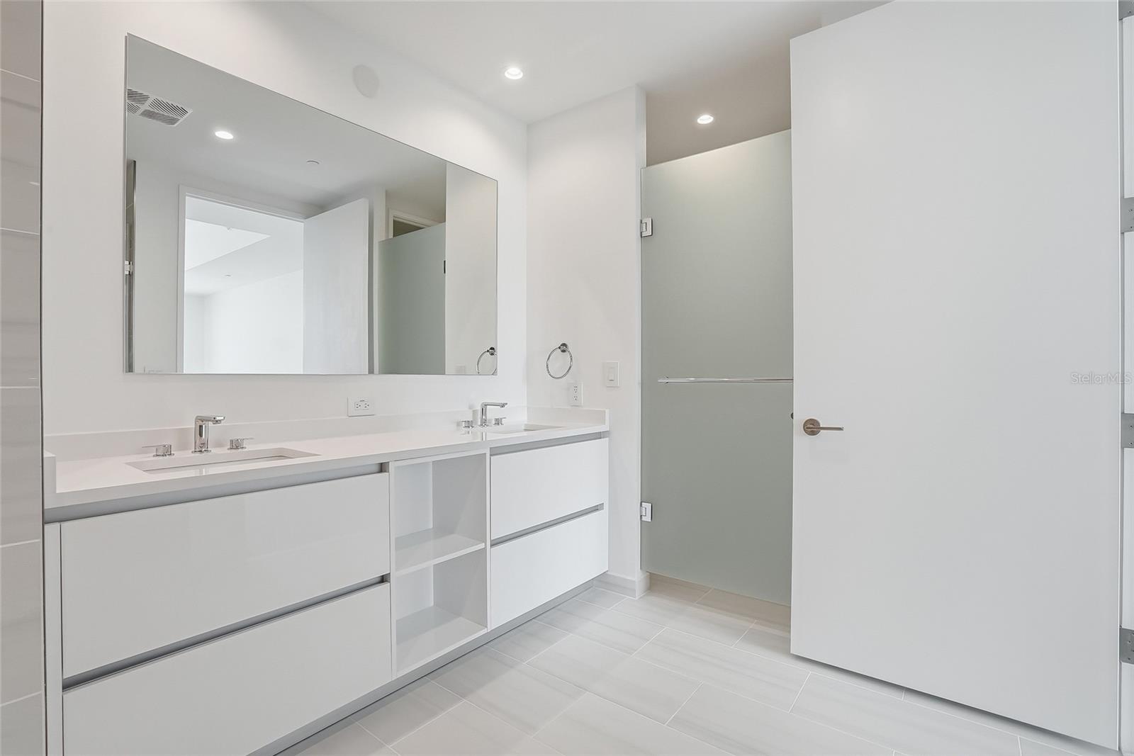 Primary bathroom double sink vanity with 4 drawers and to shelves for storage.