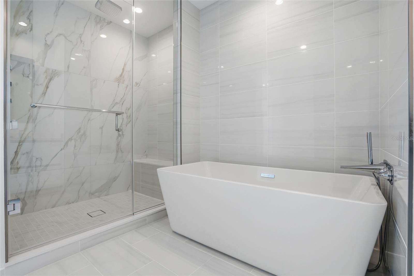 Primary bathroom with large walk-in shower, built in bench and rain head