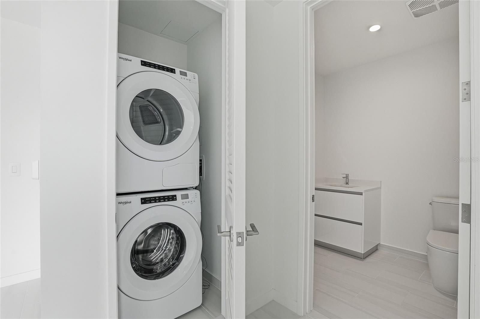 A powder bathroom and stacked Whirlpool washer and dryer are on the first floor