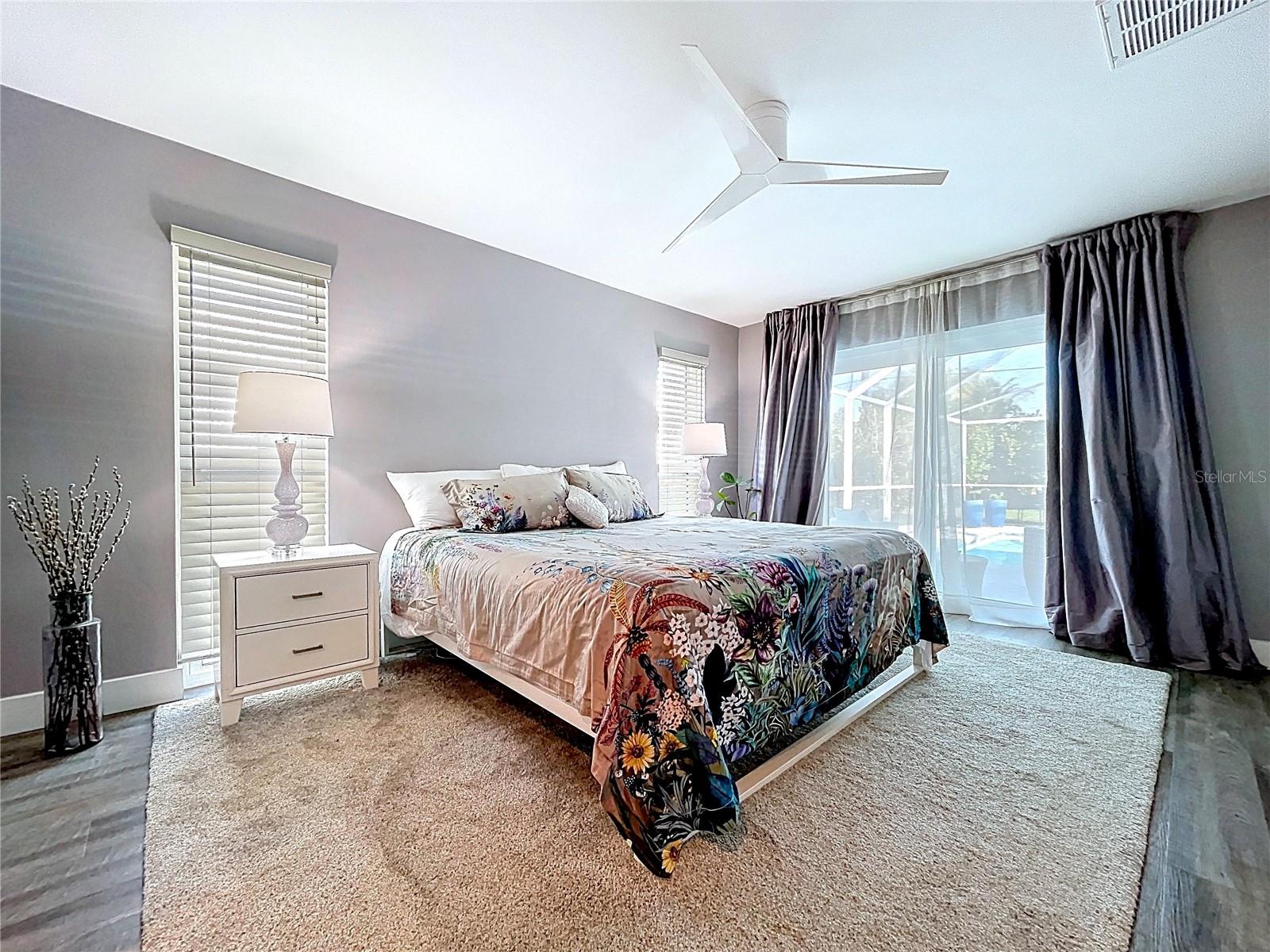 Primary bedroom is spacious and bright with a sliding glass door access to the pool deck.