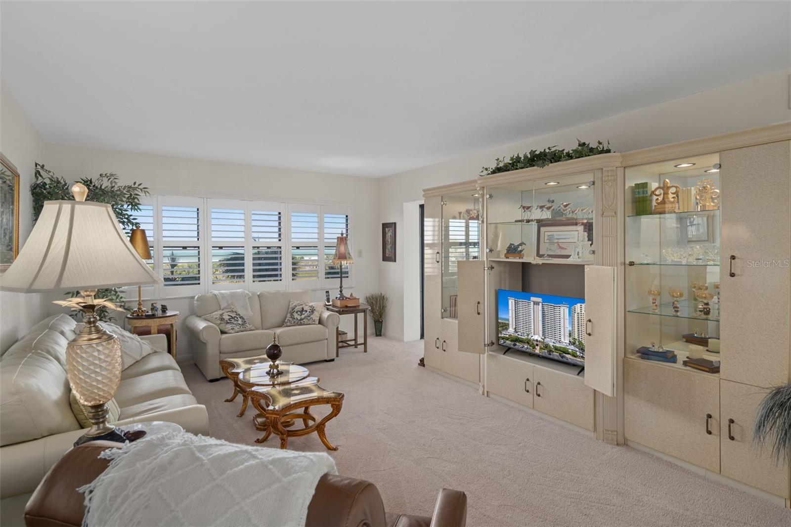 Living Room features windows with plantation shutters across the back as well as access to the patio through a sliding door.