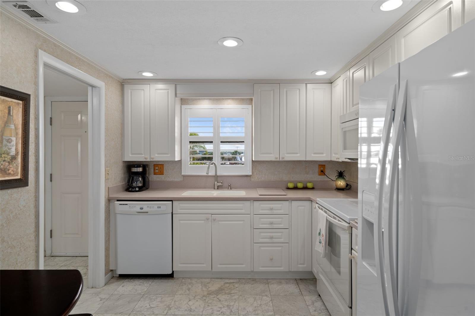 Open kitchen features Corian countertops, Whirlpool appliances and tile flooring