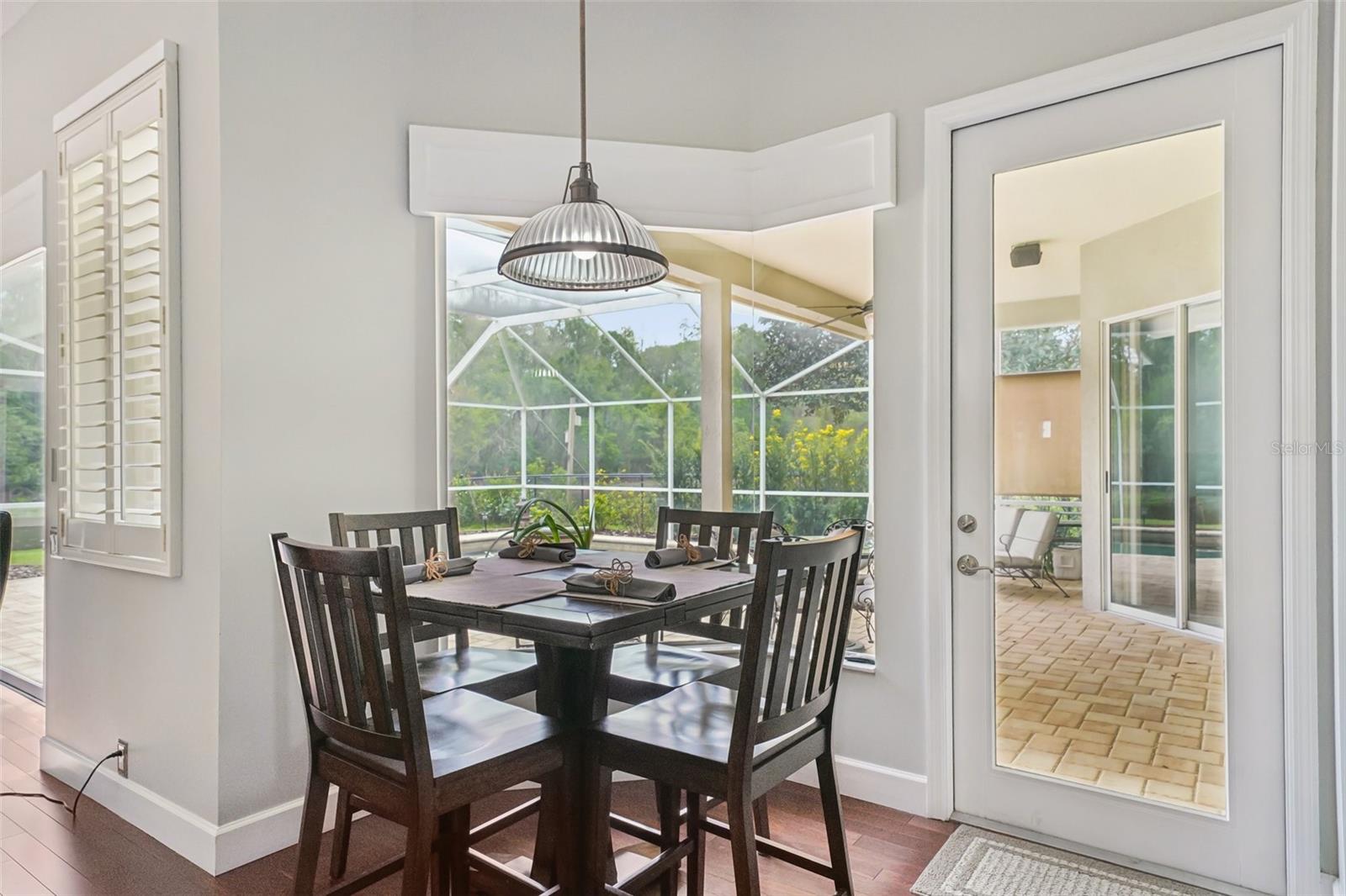an eat-in breakfast nook with mitered windows providing expansive views of the pool and conservation, recessed lighting, and a seamless flow into the family room.