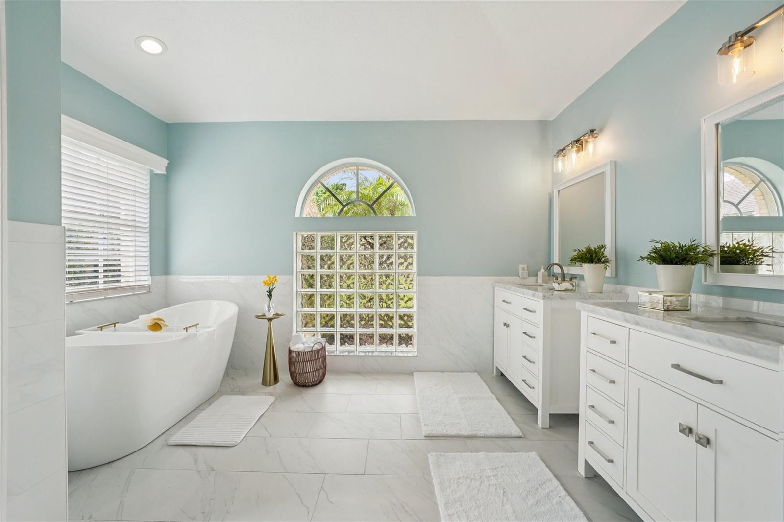 The enviable ensuite bath features marble flooring, dual vanities, a freestanding soaking tub, glass-enclosed shower, private water closet, and linen storage.