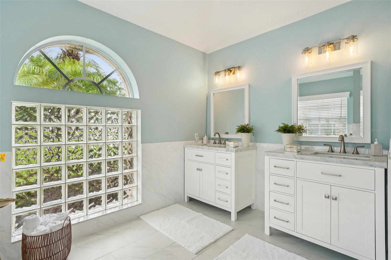 The enviable ensuite bath features marble flooring, dual vanities, a freestanding soaking tub, glass-enclosed shower, private water closet, and linen storage.