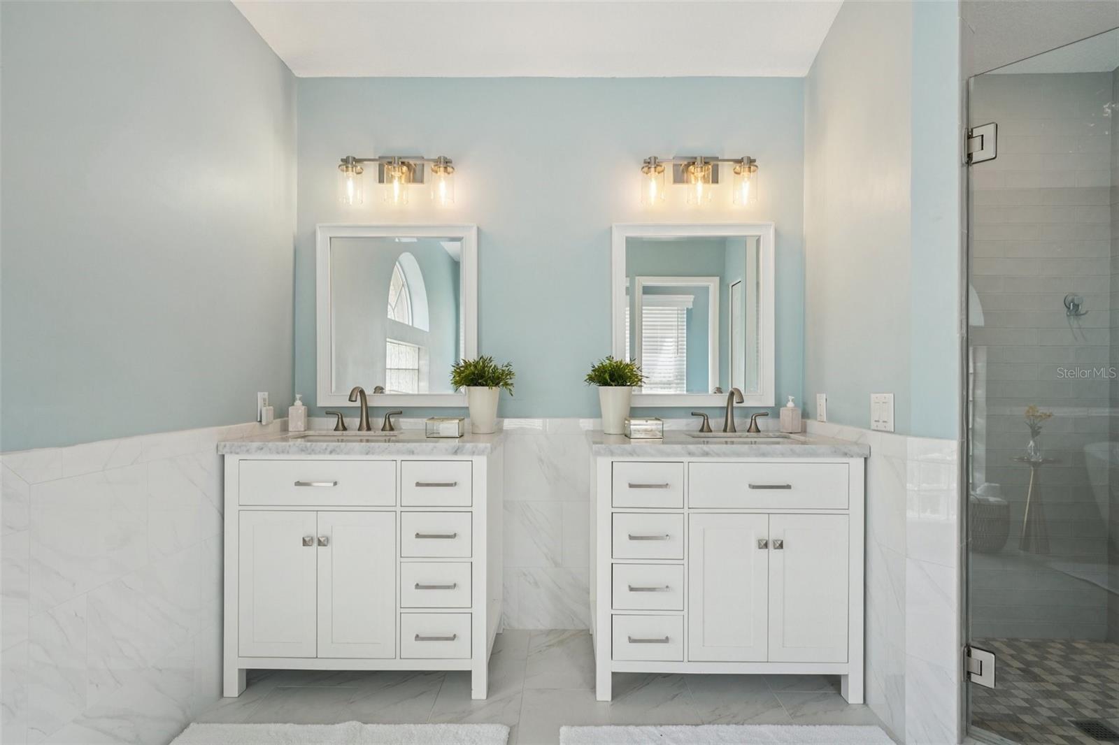 The enviable ensuite bath features marble flooring, dual vanities, a freestanding soaking tub, glass-enclosed shower, private water closet, and linen storage.