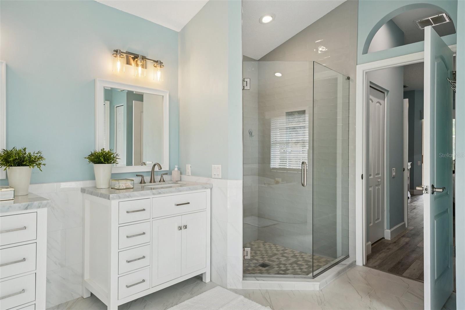 The enviable ensuite bath features marble flooring, dual vanities, a freestanding soaking tub, glass-enclosed shower, private water closet, and linen storage.