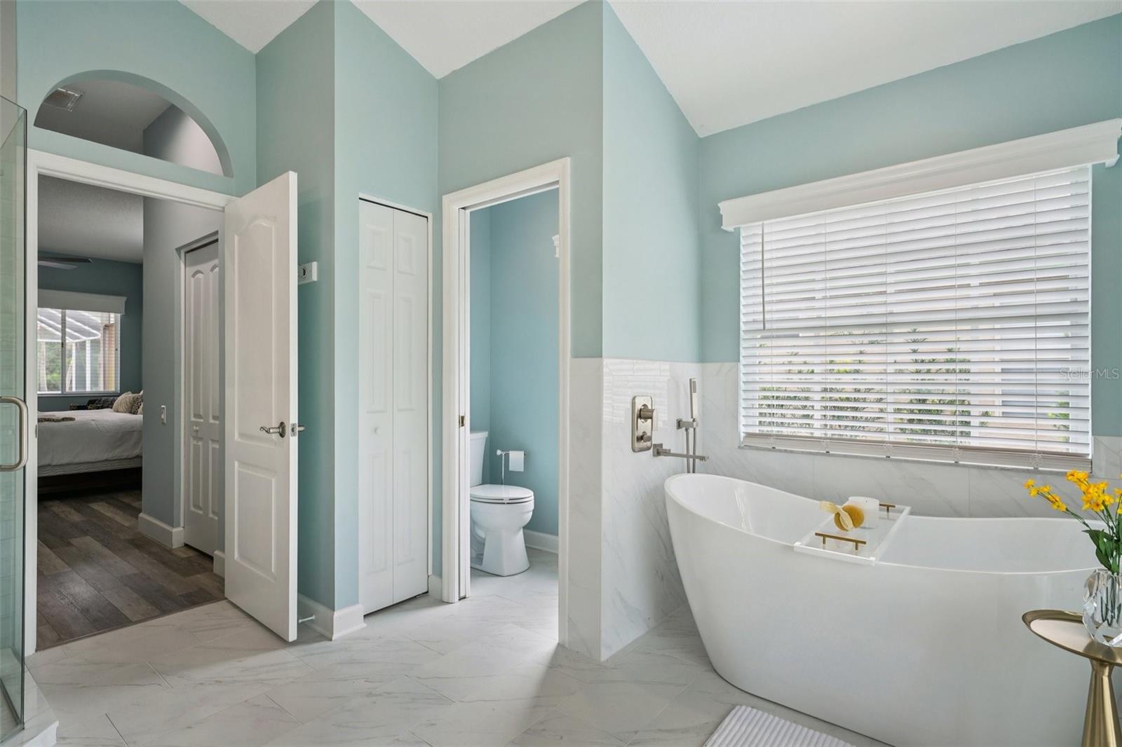 The enviable ensuite bath features marble flooring, dual vanities, a freestanding soaking tub, glass-enclosed shower, private water closet, and linen storage.