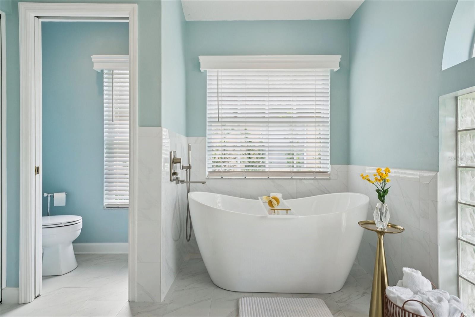 The enviable ensuite bath features marble flooring, dual vanities, a freestanding soaking tub, glass-enclosed shower, private water closet, and linen storage.