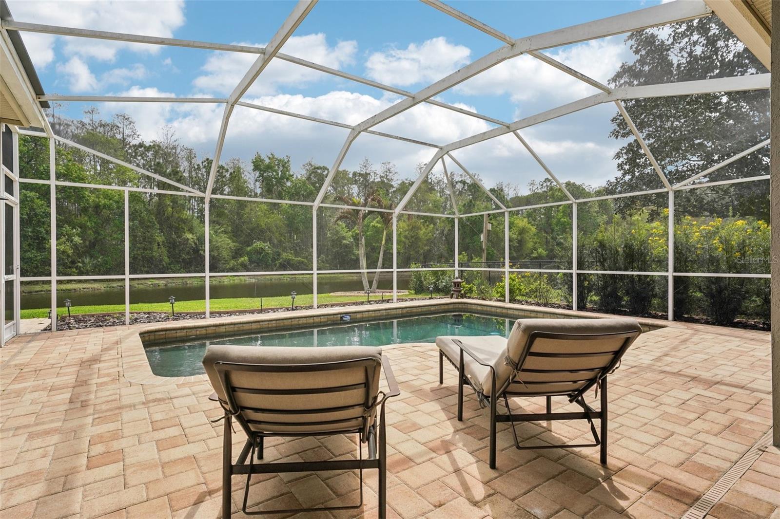 Enjoy everyday Florida living with glass sliders from multiple rooms opening to a screened pool and patio retreat. The sparkling Pebble Tec pool and surrounding paver deck with covered outdoor space offer a perfect place to relax, dine or gather with a tranquil pond and conservation backdrop. The landscaping provides privacy while preserving the view, with frequent wildlife sightings add to the natural appeal.