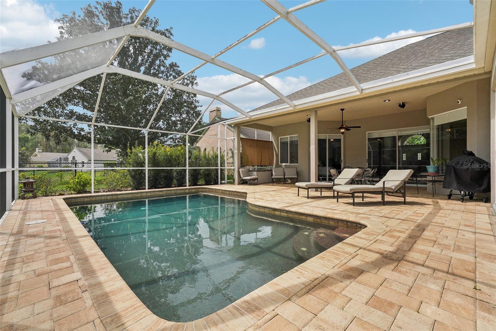 Enjoy everyday Florida living with glass sliders from multiple rooms opening to a screened pool and patio retreat. The sparkling Pebble Tec pool and surrounding paver deck with covered outdoor space offer a perfect place to relax, dine or gather with a tranquil pond and conservation backdrop. The landscaping provides privacy while preserving the view, with frequent wildlife sightings add to the natural appeal.