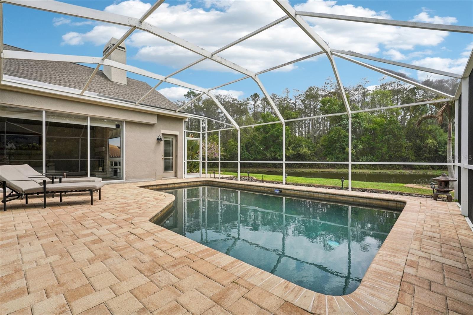 Enjoy everyday Florida living with glass sliders from multiple rooms opening to a screened pool and patio retreat. The sparkling Pebble Tec pool and surrounding paver deck with covered outdoor space offer a perfect place to relax, dine or gather with a tranquil pond and conservation backdrop. The landscaping provides privacy while preserving the view, with frequent wildlife sightings add to the natural appeal.