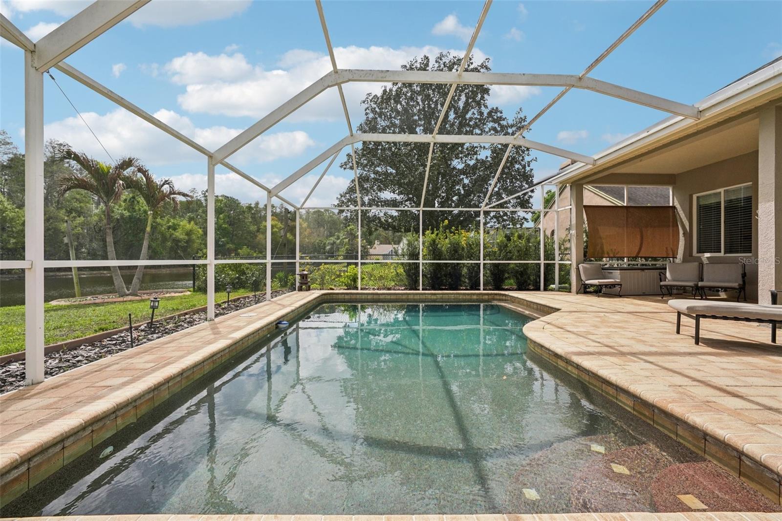 Enjoy everyday Florida living with glass sliders from multiple rooms opening to a screened pool and patio retreat. The sparkling Pebble Tec pool and surrounding paver deck with covered outdoor space offer a perfect place to relax, dine or gather with a tranquil pond and conservation backdrop. The landscaping provides privacy while preserving the view, with frequent wildlife sightings add to the natural appeal.