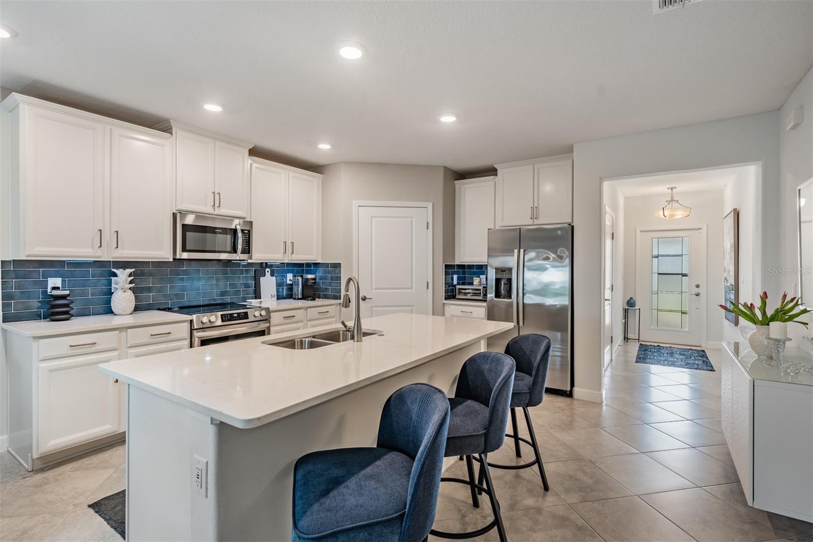 Loads of cabinets with crown molding, glass backsplash, quartz island and built in buffet