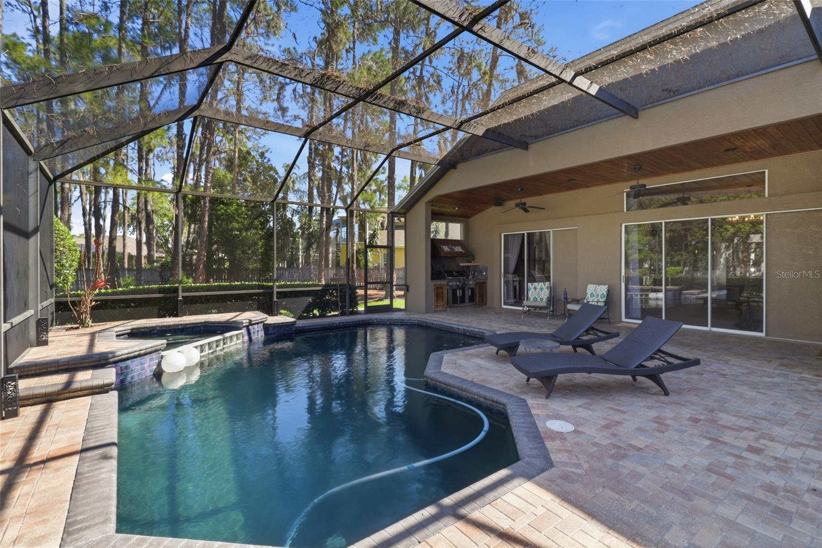 Private screened pool and spa with covered lanai, paver patio, and space for outdoor living and entertaining