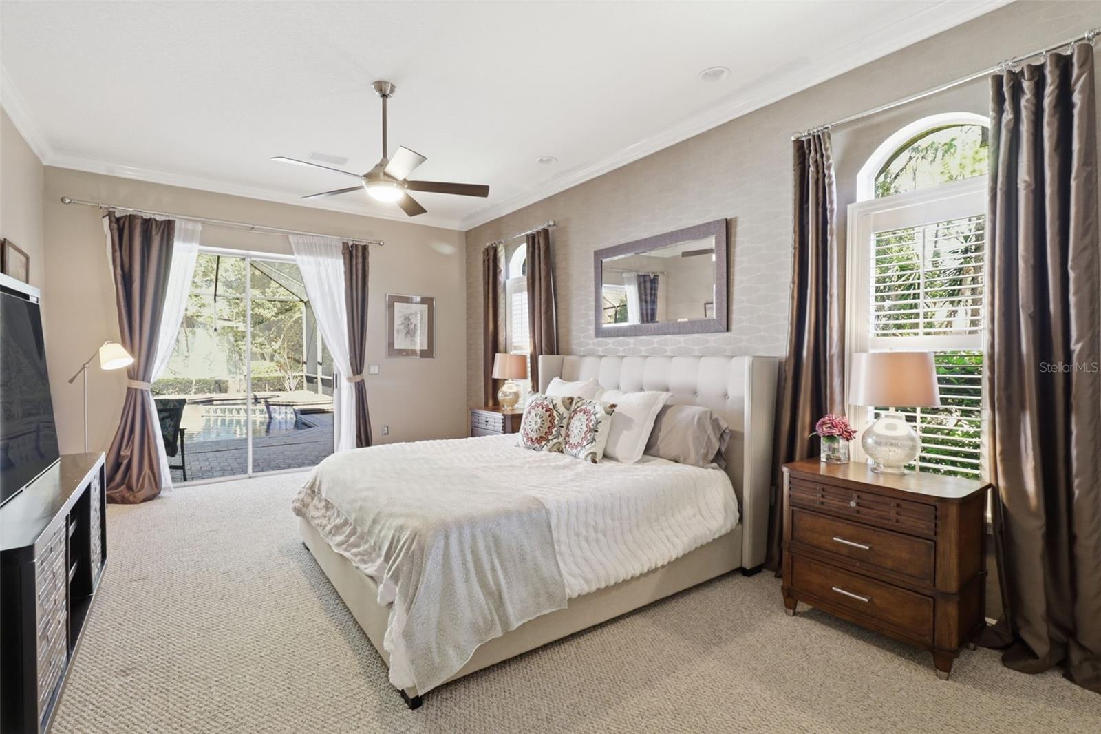 Primary suite with natural light, plantation shutters, and direct access to the pool area