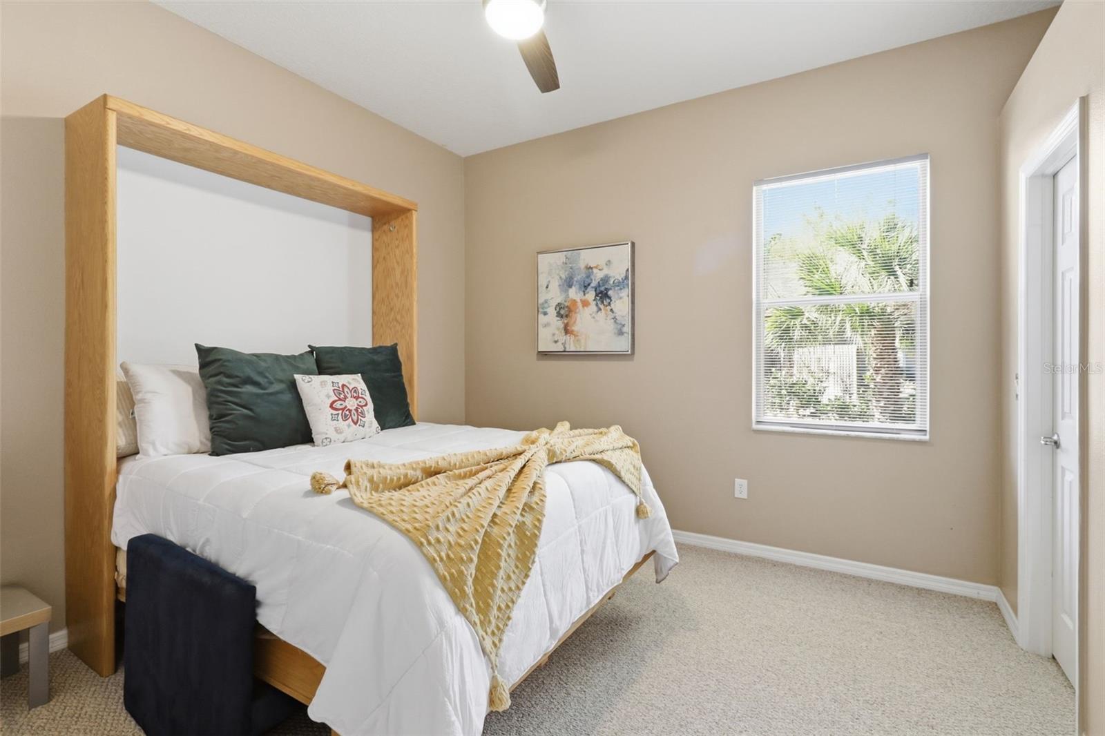 Bright secondary bedroom featuring a walk-in closet and abundant natural light
