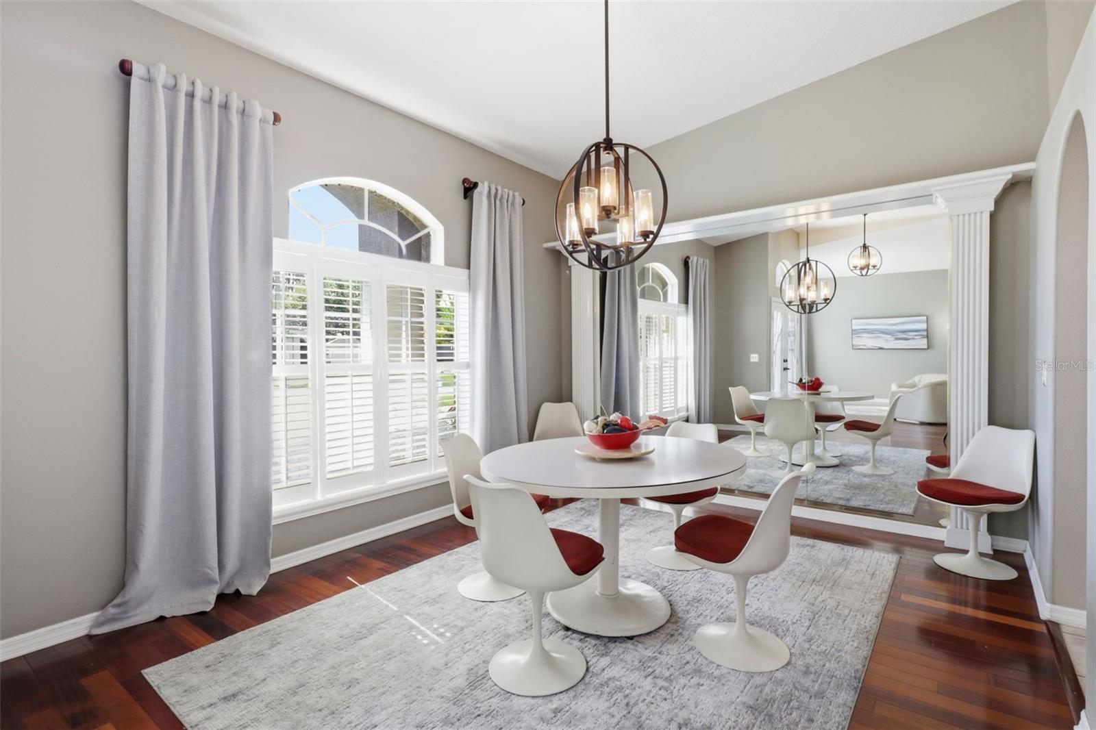 Elegant formal dining room featuring wood floors, designer lighting, and plantation shutters