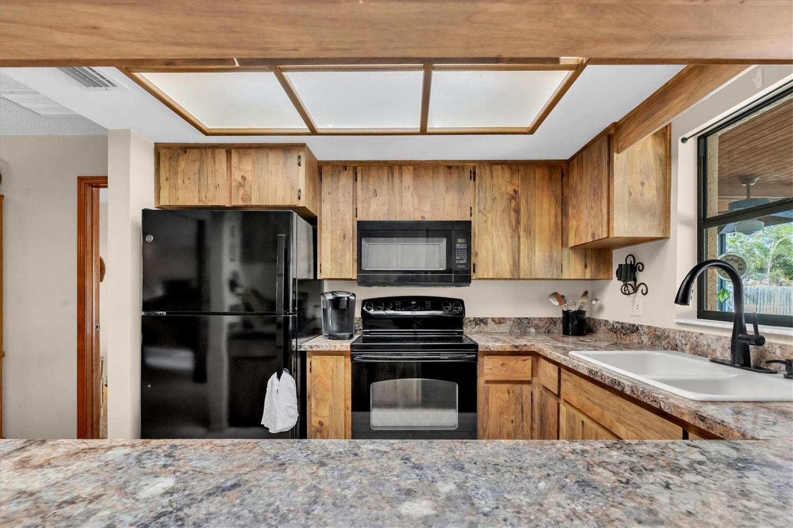 Kitchen has tiled floors and black appliances including Dishwasher, Microwave, Range, and Refrigerator
