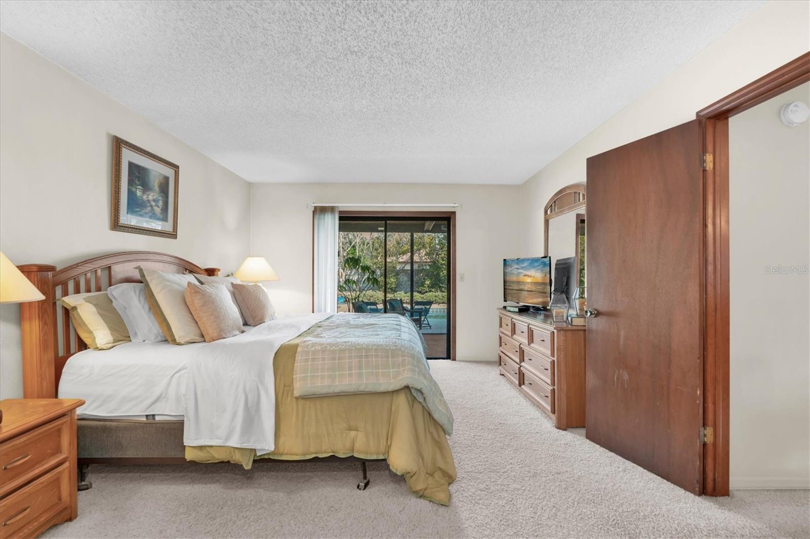 Primary Bedroom with Walk-in closet, dressing area, sliders leading to screened porch, and ensuite bath