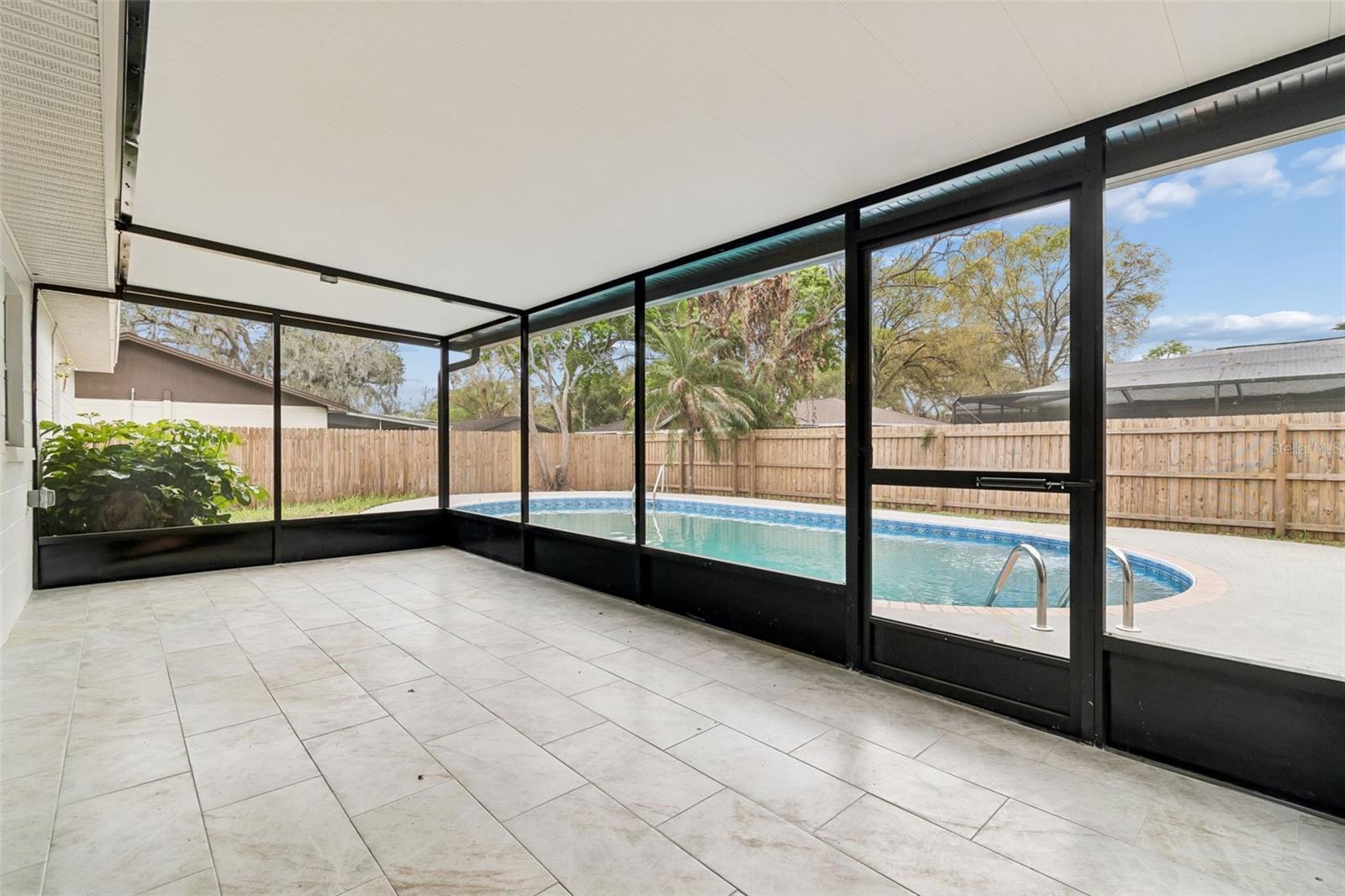 Screened rear patio with ample seating space, ideal for enjoying outdoor living while remaining protected from the elements.