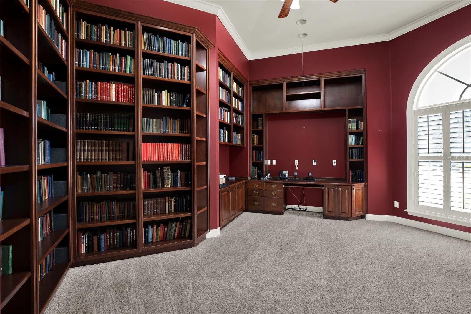 Floor to ceiling built-in bookshelves and desk with room for an additional freestanding desk.