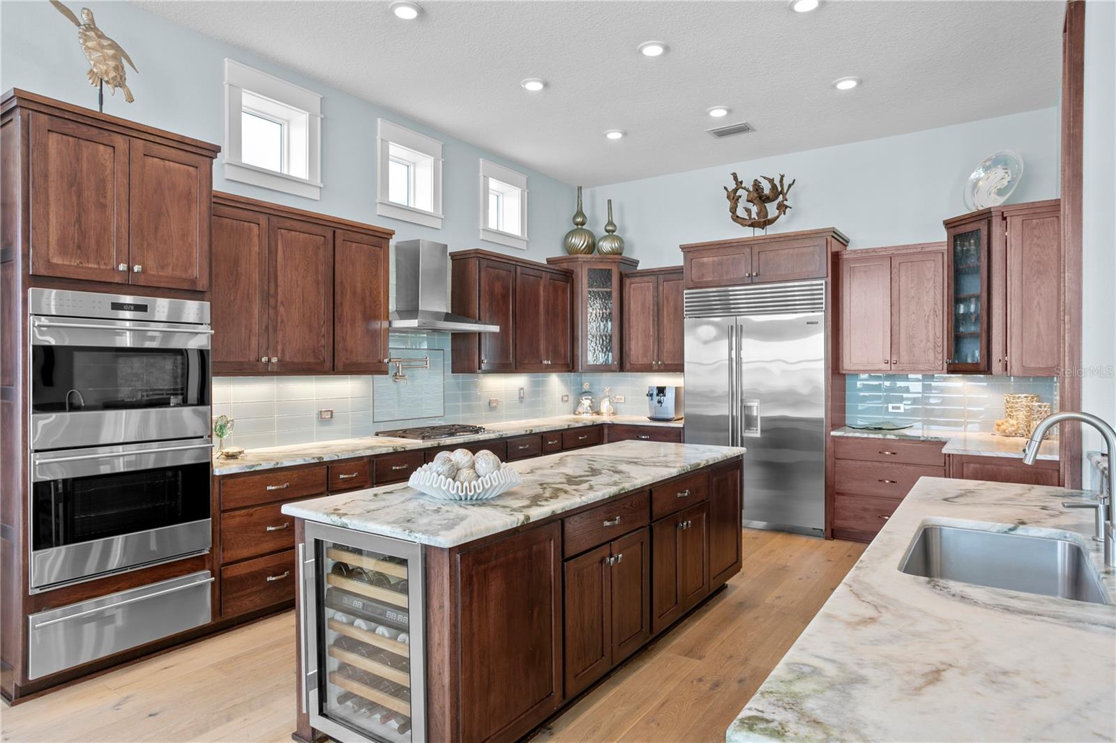 A chef's delight kitchen with rich custom crafted cabinets adorned with natural stone to connect to the water and beach.  Wolf and Subzero appliances; gas cooking; double ovens, warming drawer, wine refrigeration so that everything is at your fingertips.